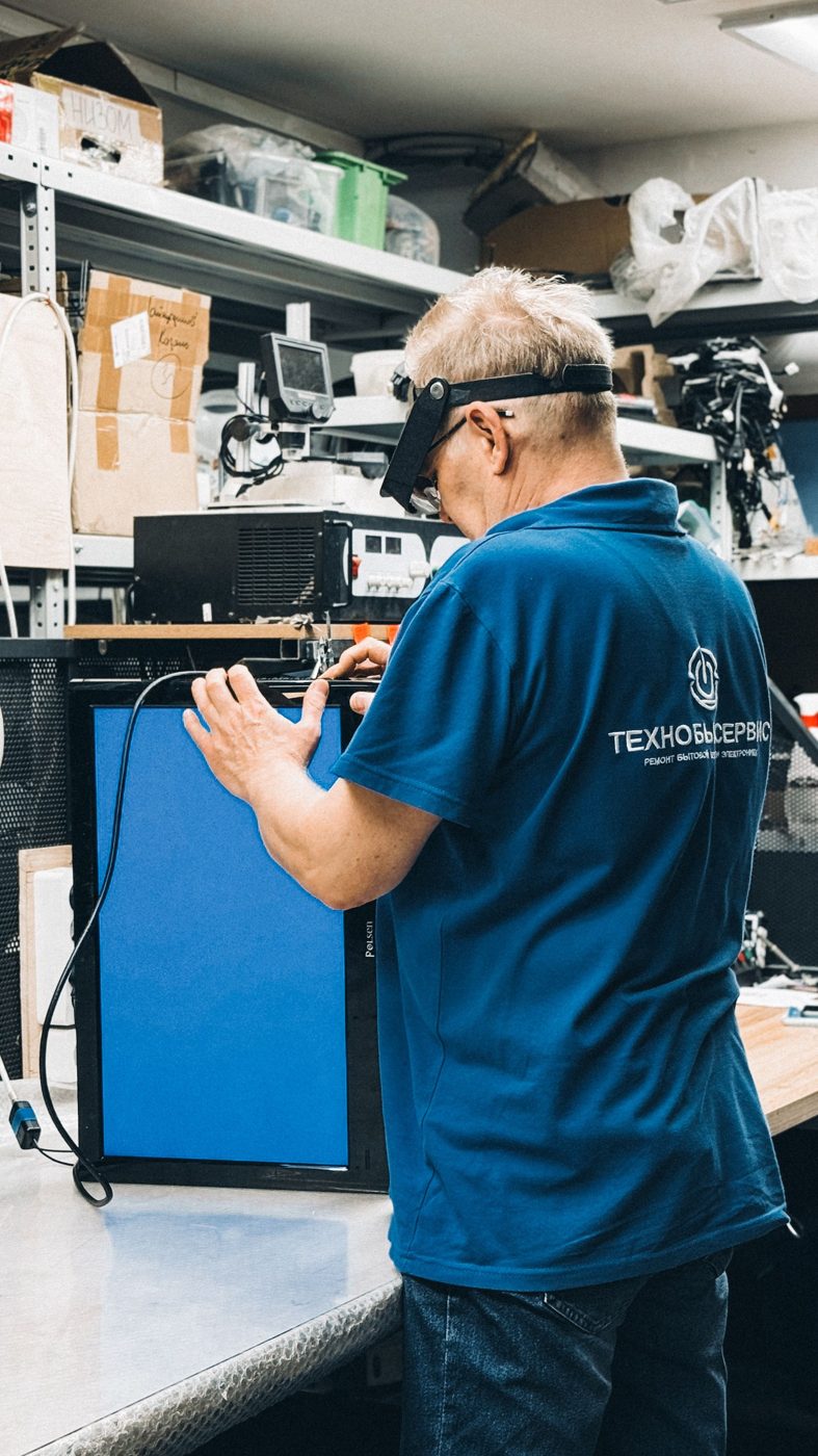 A technician handles computer equipment in a workshop.