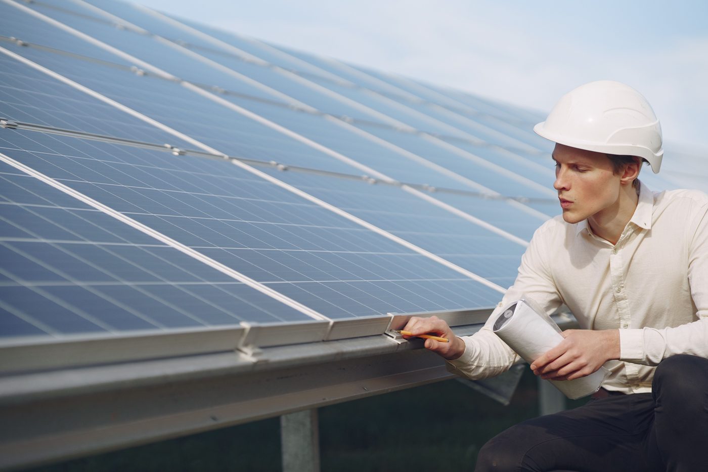 A worker in a hard hat inspects solar panels.