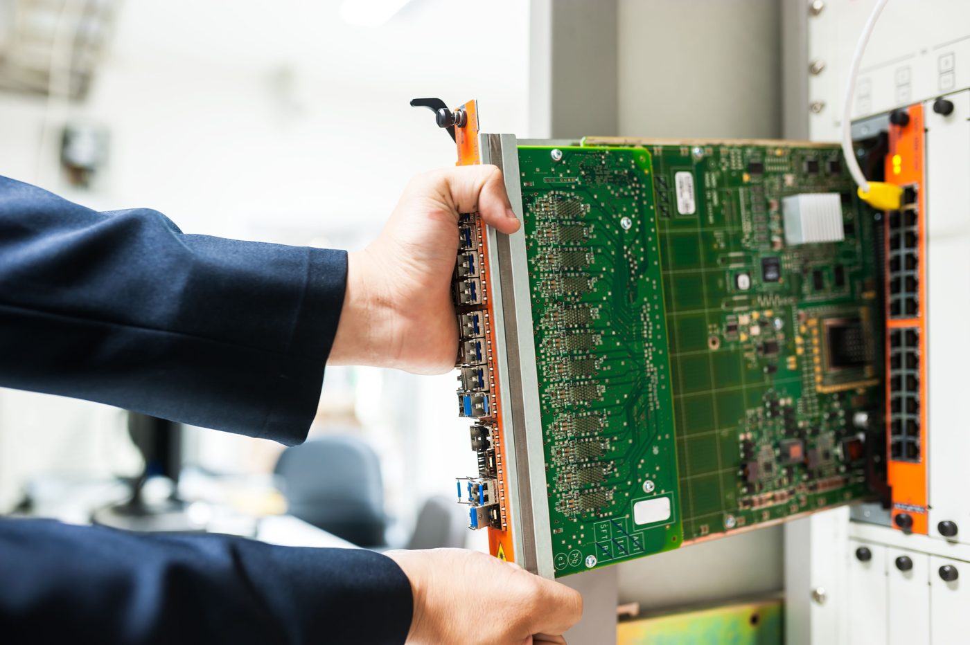 A technician fits a component into a network rack.