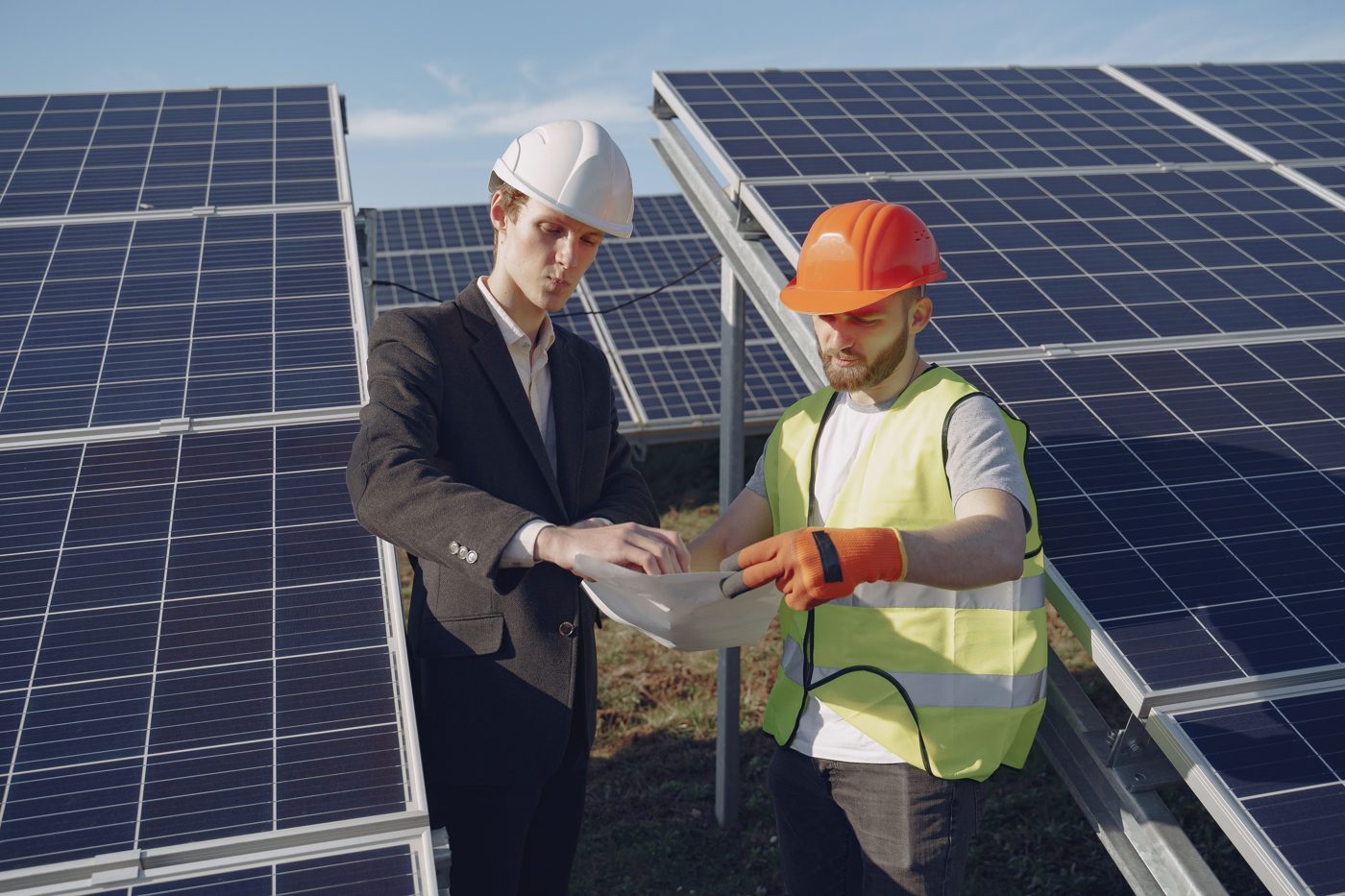Two people review documentation beside solar panels.